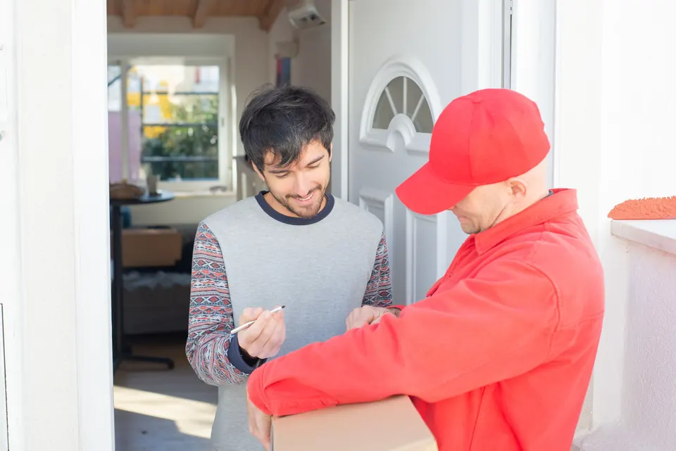 Un livreur remet un colis à un client devant sa porte