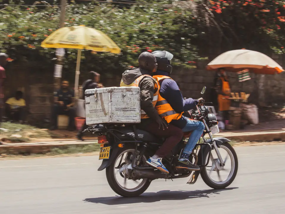 Un livreur à moto avec un caisson de livraison, dans une rue de Nairobi
